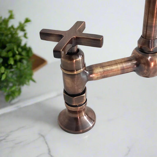 Antique copper kitchen bridge faucet with tall gooseneck spout and separate side sprayer on marble countertop
