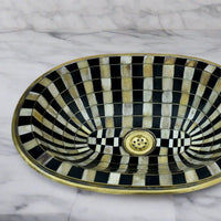 Close-up of the handcrafted brass sink showing detailed resin and bone inlays in a checkerboard pattern