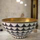 Top view of a handcrafted brass bowl sink with black and white Moroccan mosaic accents, showcasing the intricate geometric pattern and hammered brass interior