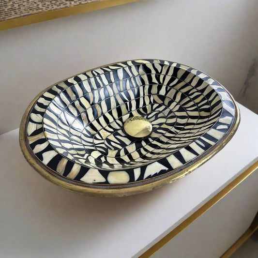 Close-up of the intricate black and white bone inlay pattern on a handcrafted brass bathroom sink from Morocco
