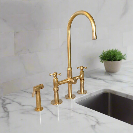 Elegant brass kitchen faucet set with side spray hose installed on white marble countertop with backsplash and potted plant